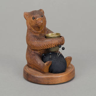 Carved, seated bear w/ brass thimble and pin cushion