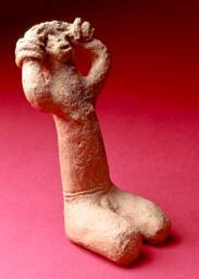 Crudely formed ceramic figure, Bambara; color is stained gray-brown, with a darkened area over …